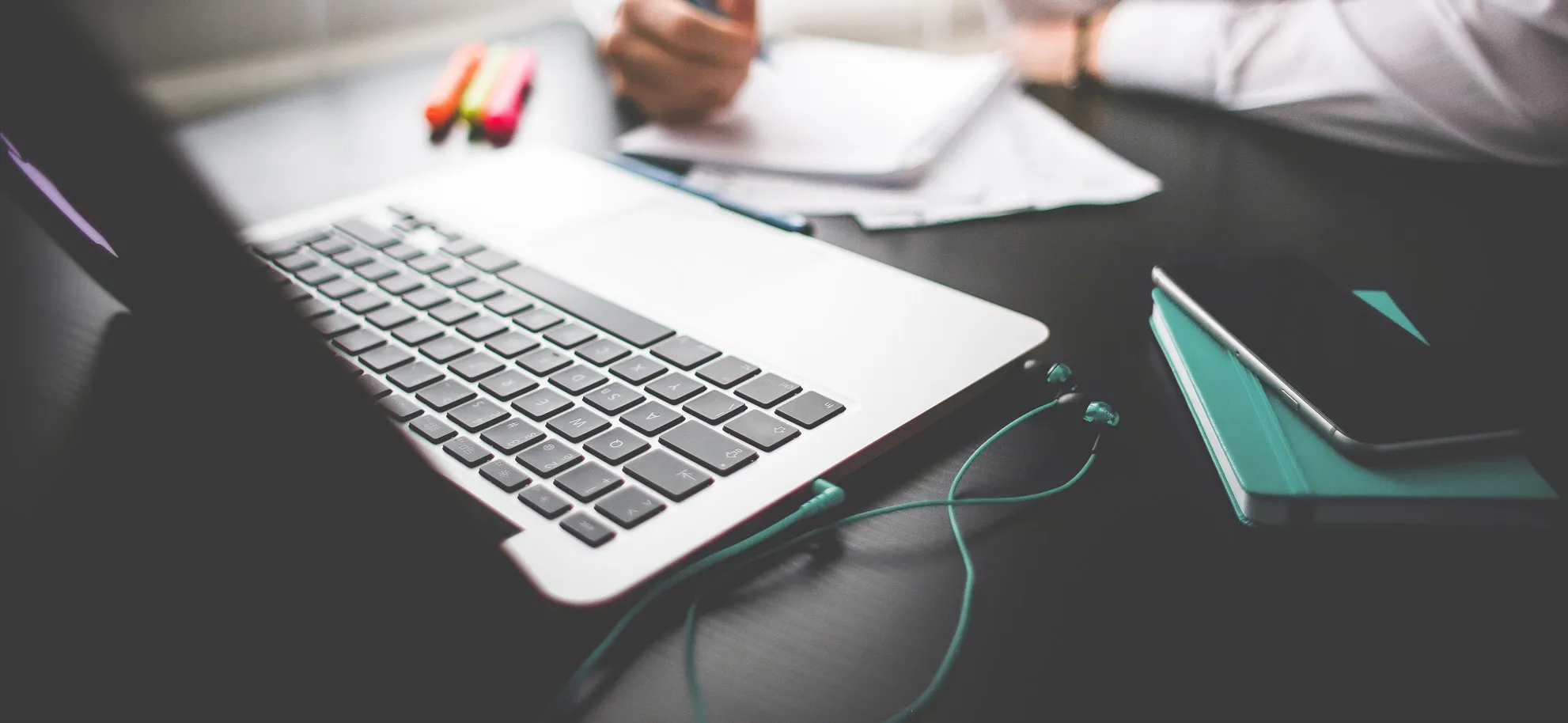 Laptop, Smartphone und Notizen auf einem Schreibtisch: Betreuung von Webseiten durch die pixagentur